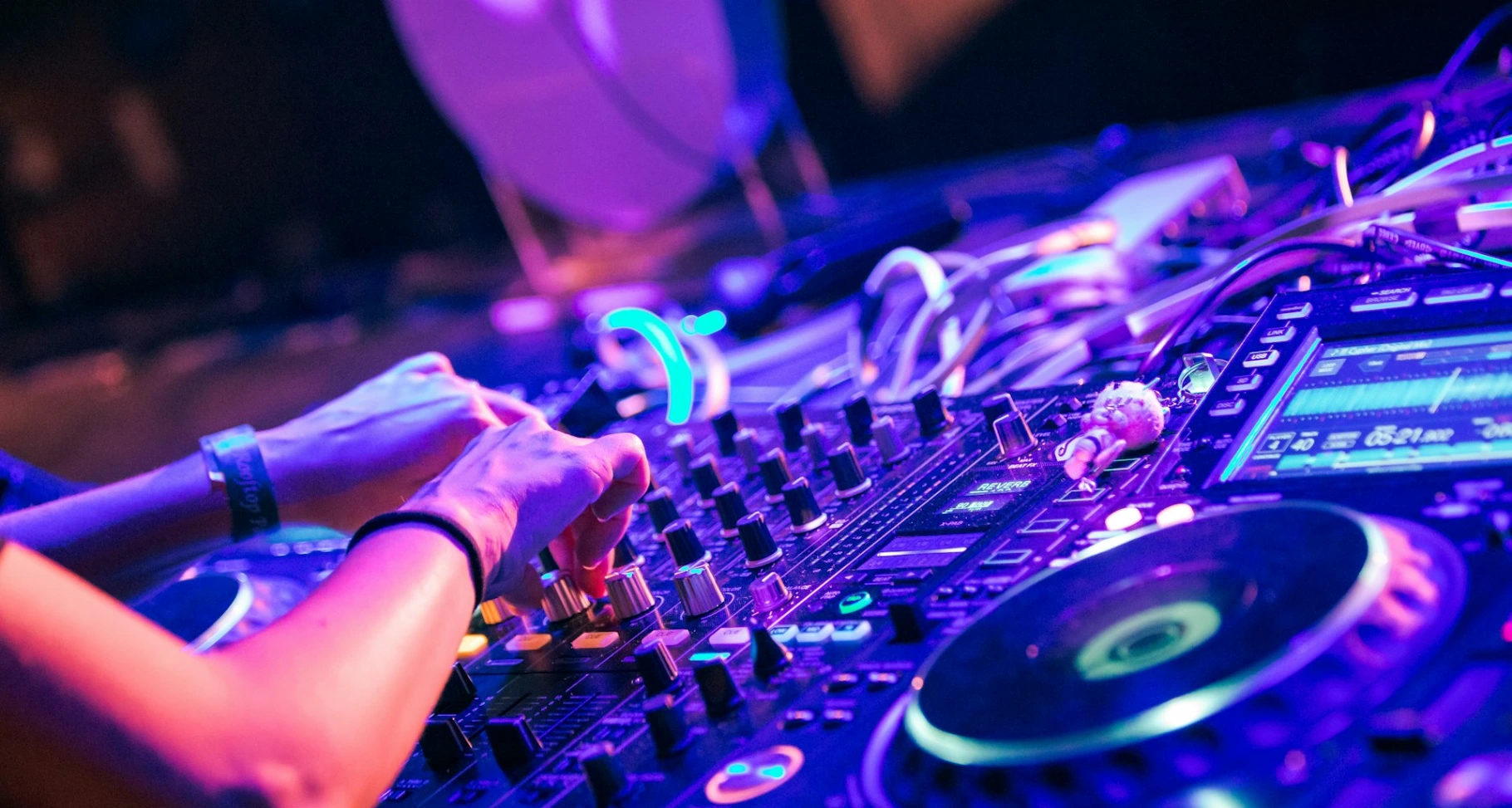 person playing dj controller with purple lights
